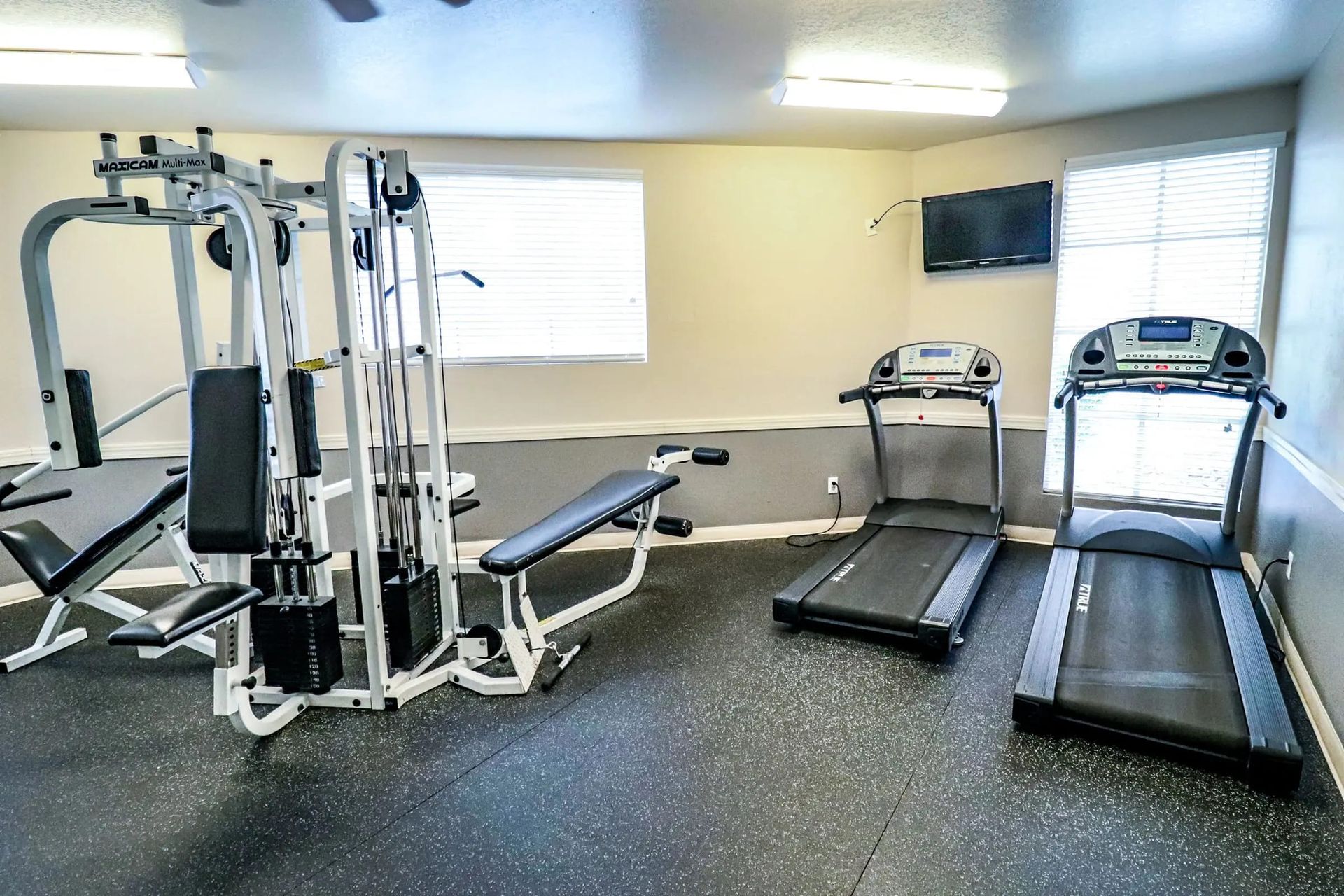 A gym with treadmills, a bench, and a weight machine.