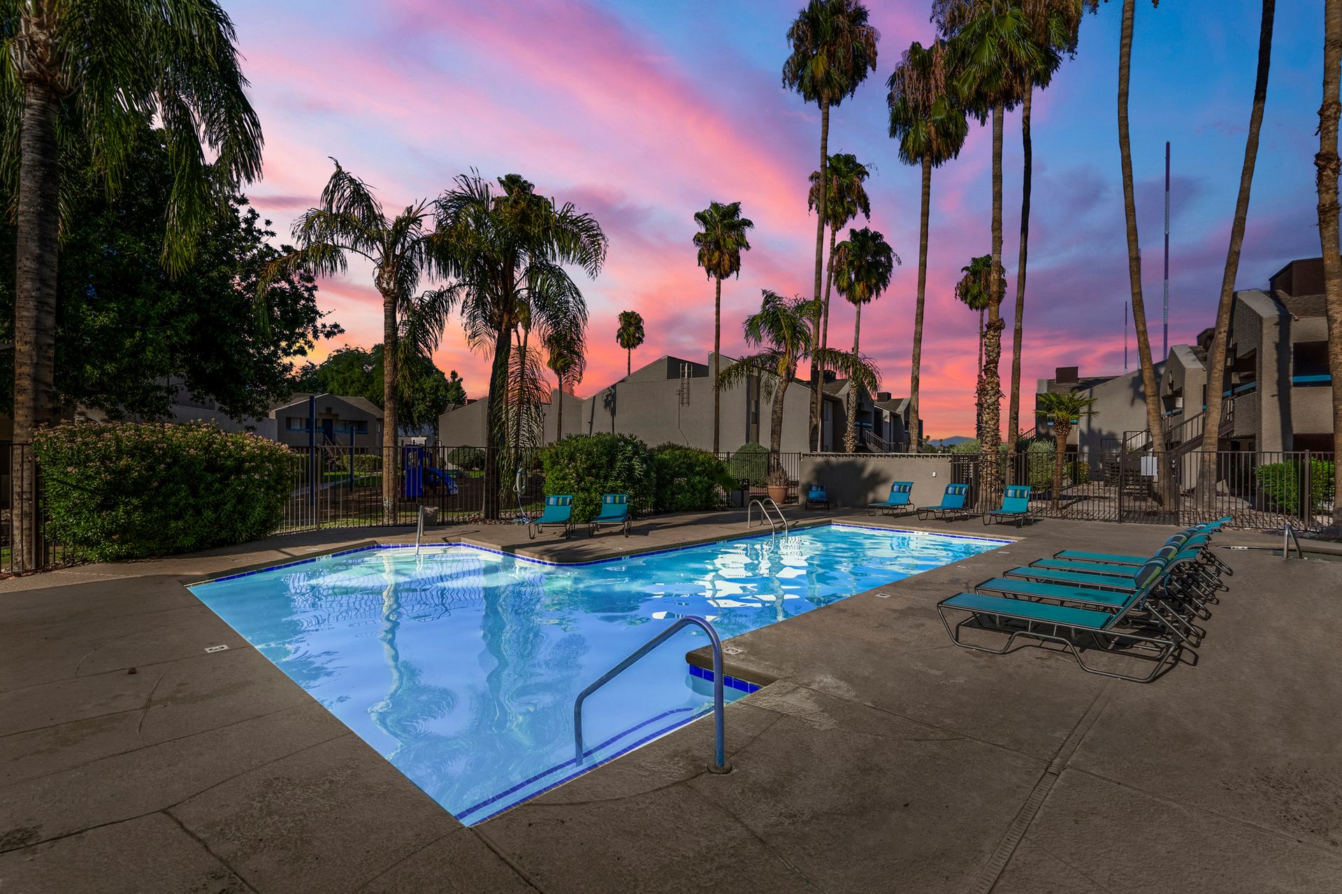 Swimming pool and lounge chairs under palms at dusk